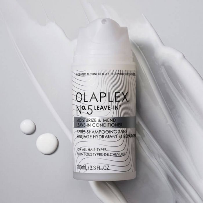 bottle of olaplex no 5 on a cream smeared background and two drops of shampoo