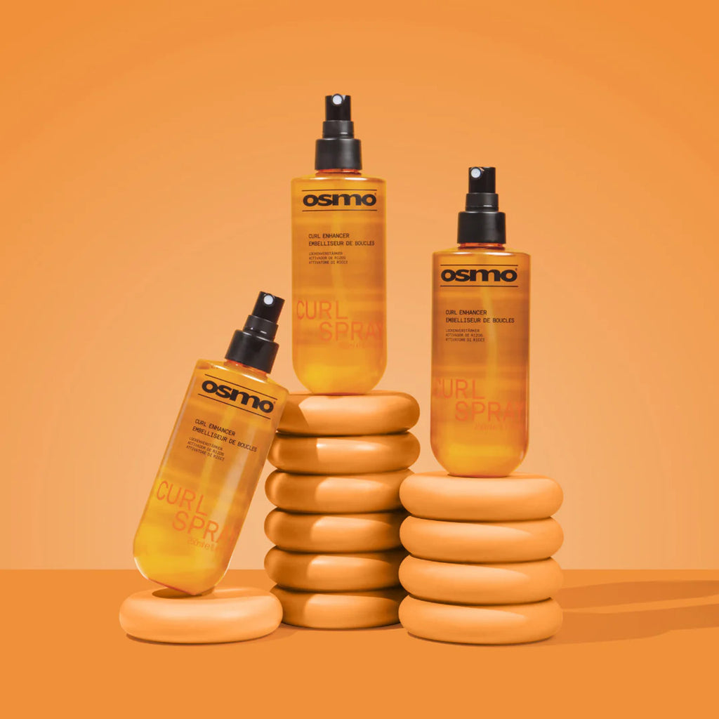 Three bottles of Osmo Curl Spray on an orange background
