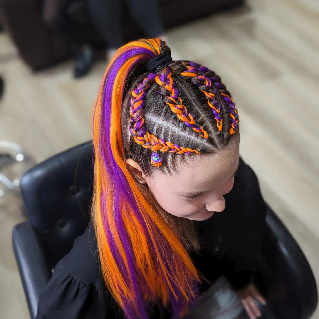 Person with colorful braided hair in a salon setting