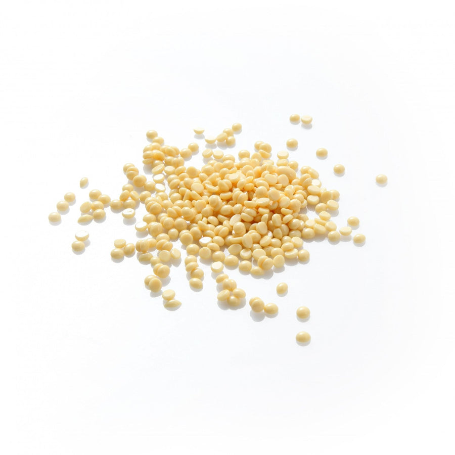 Yellow wax pellets scattered on a white background
