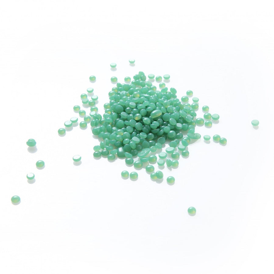 Green wax pellets scattered on a white background