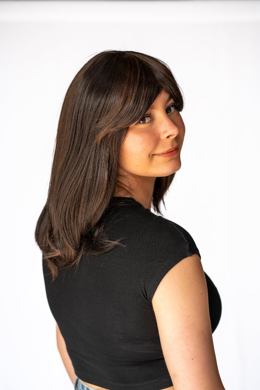 Woman wearing synthetic dark brown shoulder length wig, showing the back view