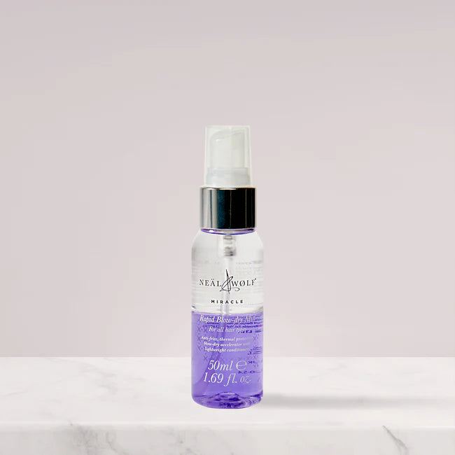 Neat & Wolf mini spray bottle on a white surface with a light pink background