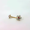 Gold belly button ring with floral design and red gemstones on a white background