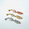Three belly button rings with leaf-shaped pendants on a white background