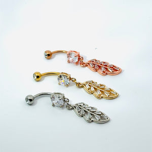 Three belly button rings with leaf-shaped pendants on a white background