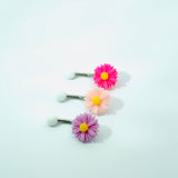 Three floral belly buttons with pink, purple, and pink flowers on a white background