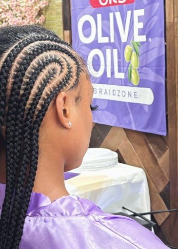 Person with braided hair in front of an Olive Oil Braidzone sign.