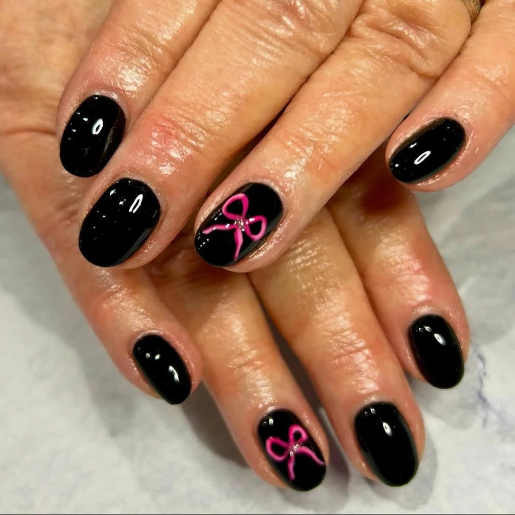 Black nail polish with pink bow design on a white background