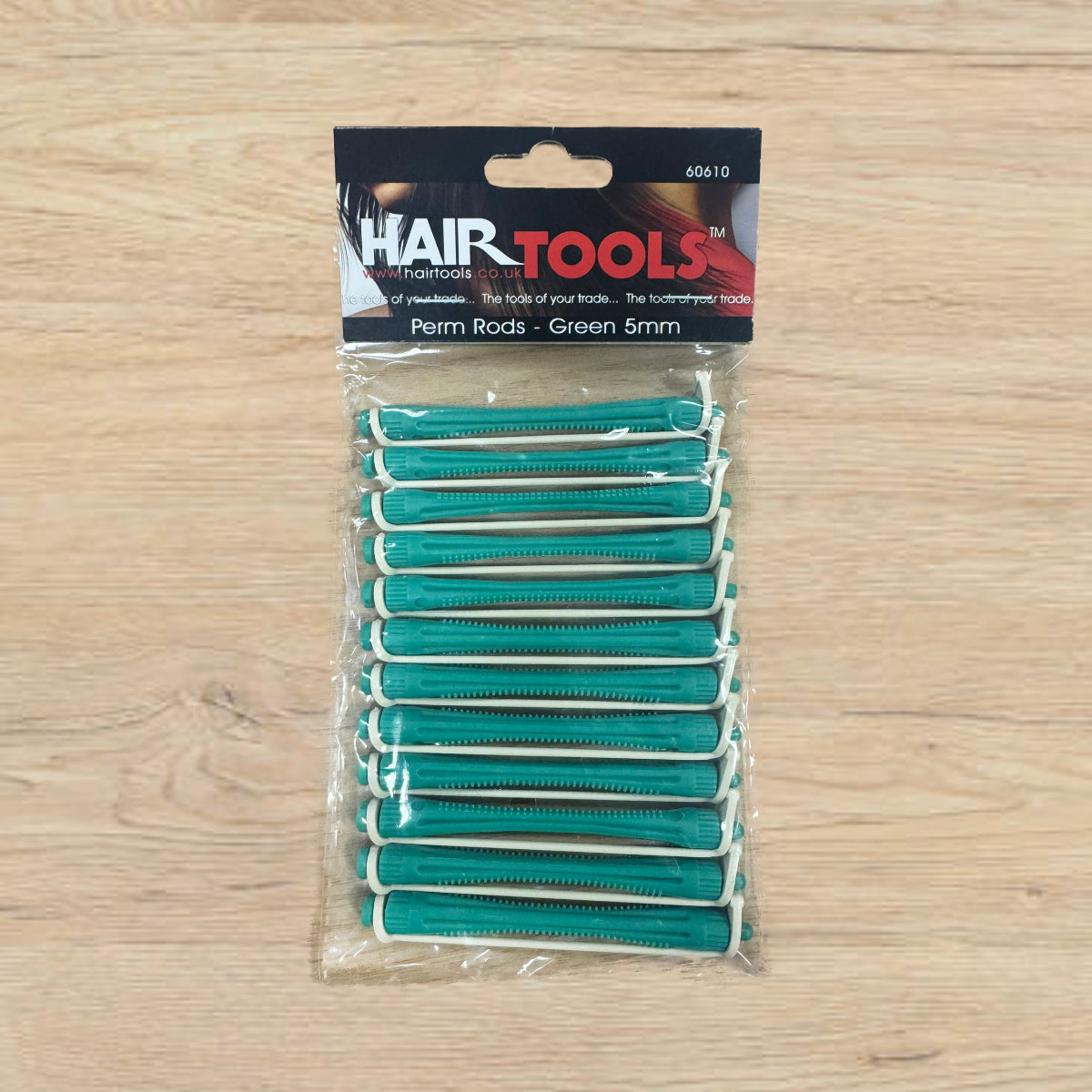 Pack of green hair perm rods with 'Hair Tools' packaging on a wooden surface