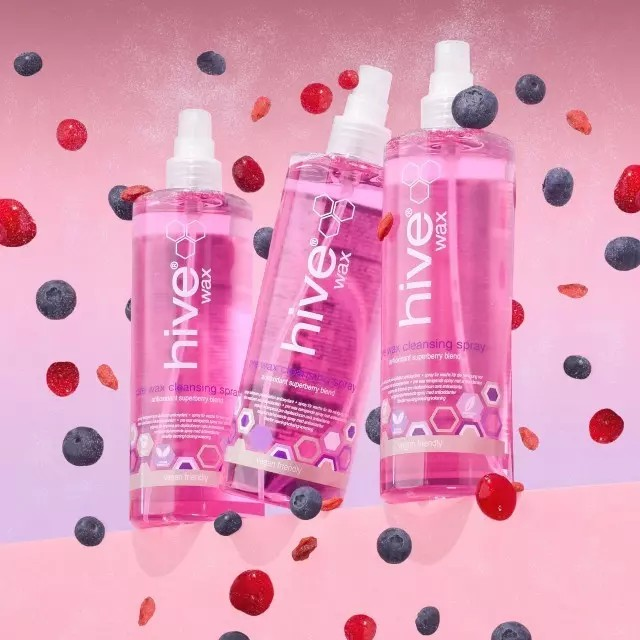 2 bottles of hive wax pre wax cleansing spray. the bottles are clear with pink liquid and they are surrounded by red and blue berries