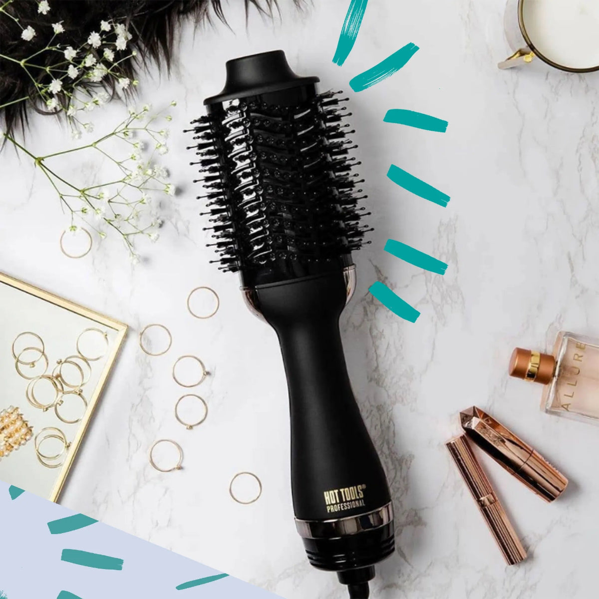 Black hair styling tool on a marble surface with jewelry and flowers.
