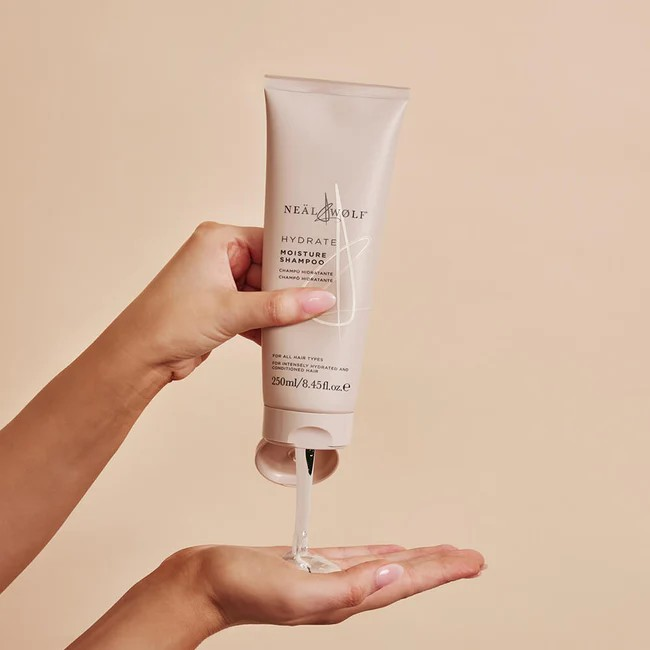 neal and wolf branded beige squeeze tube being held and squeezed into an open palm