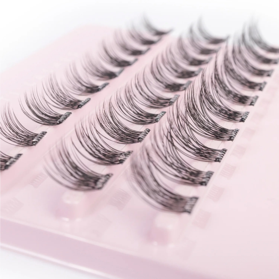 close up of tatti lash branded eyelash clusters on a pink base